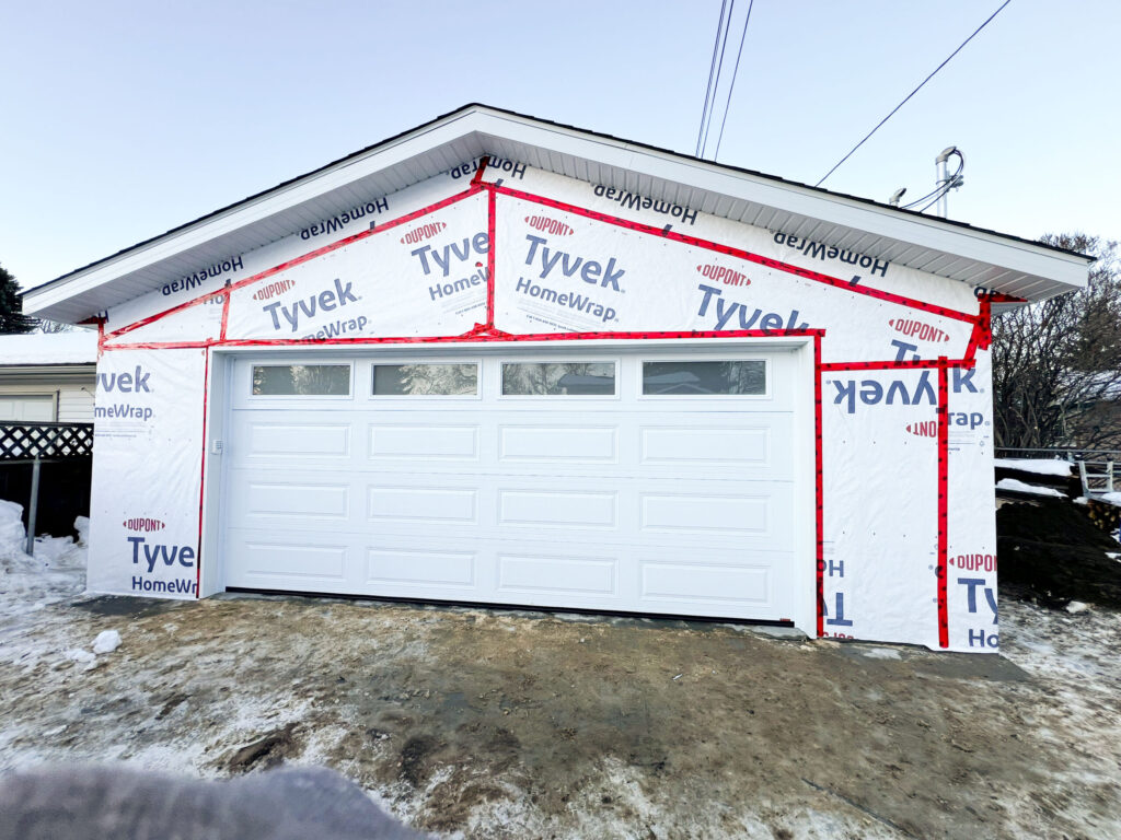 Detached garage in Edmonton with insulated overhead garage door installed and Tyvek housewrap in place by Alberta Builder Services