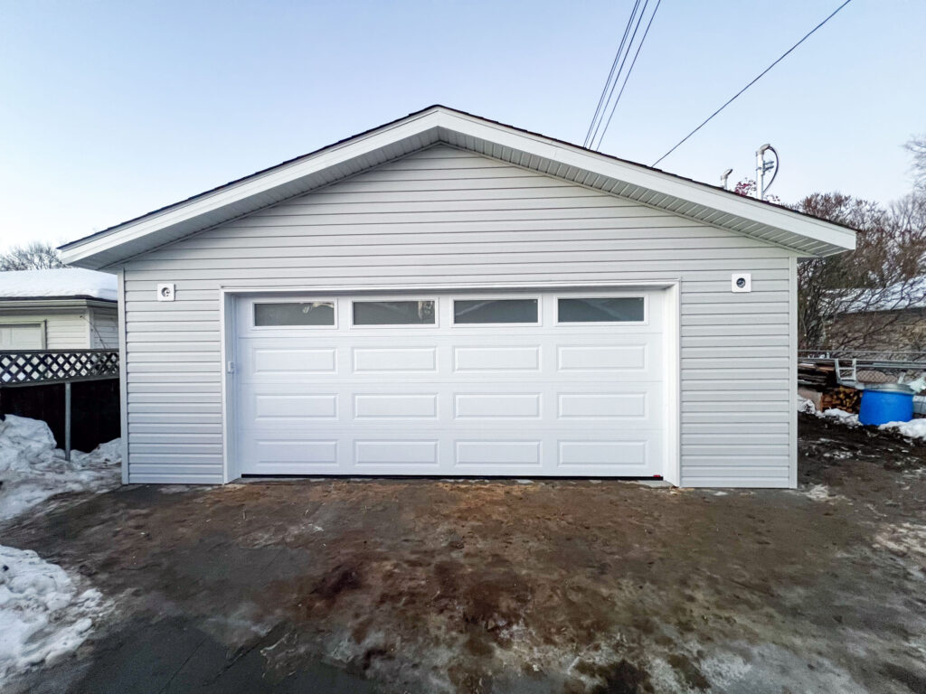 Completed detached garage in Edmonton with vinyl siding, soffit, fascia, and insulated overhead garage door by Alberta Builder Services