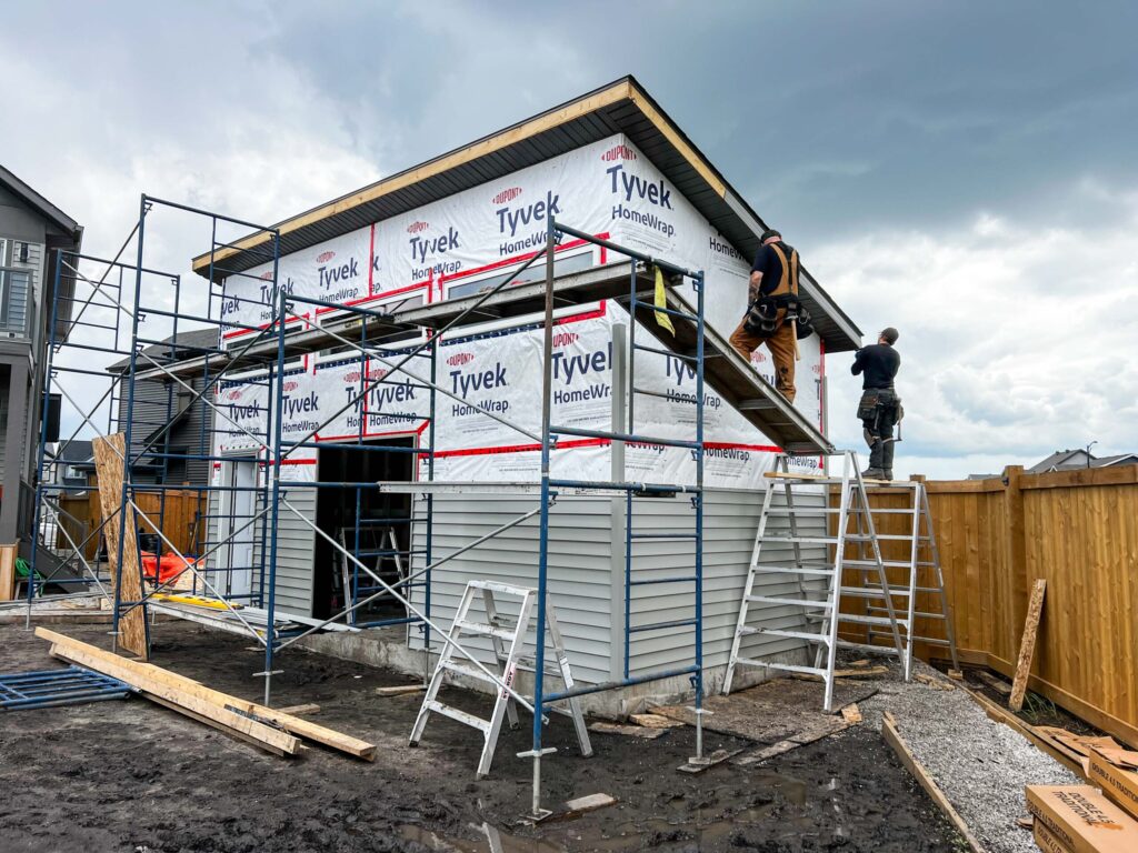 Construction of a custom oversized detached backyard shed with weather barrier, scaffolding, and exterior finishing in the Greater Edmonton area by Alberta Builder Services Ltd.
